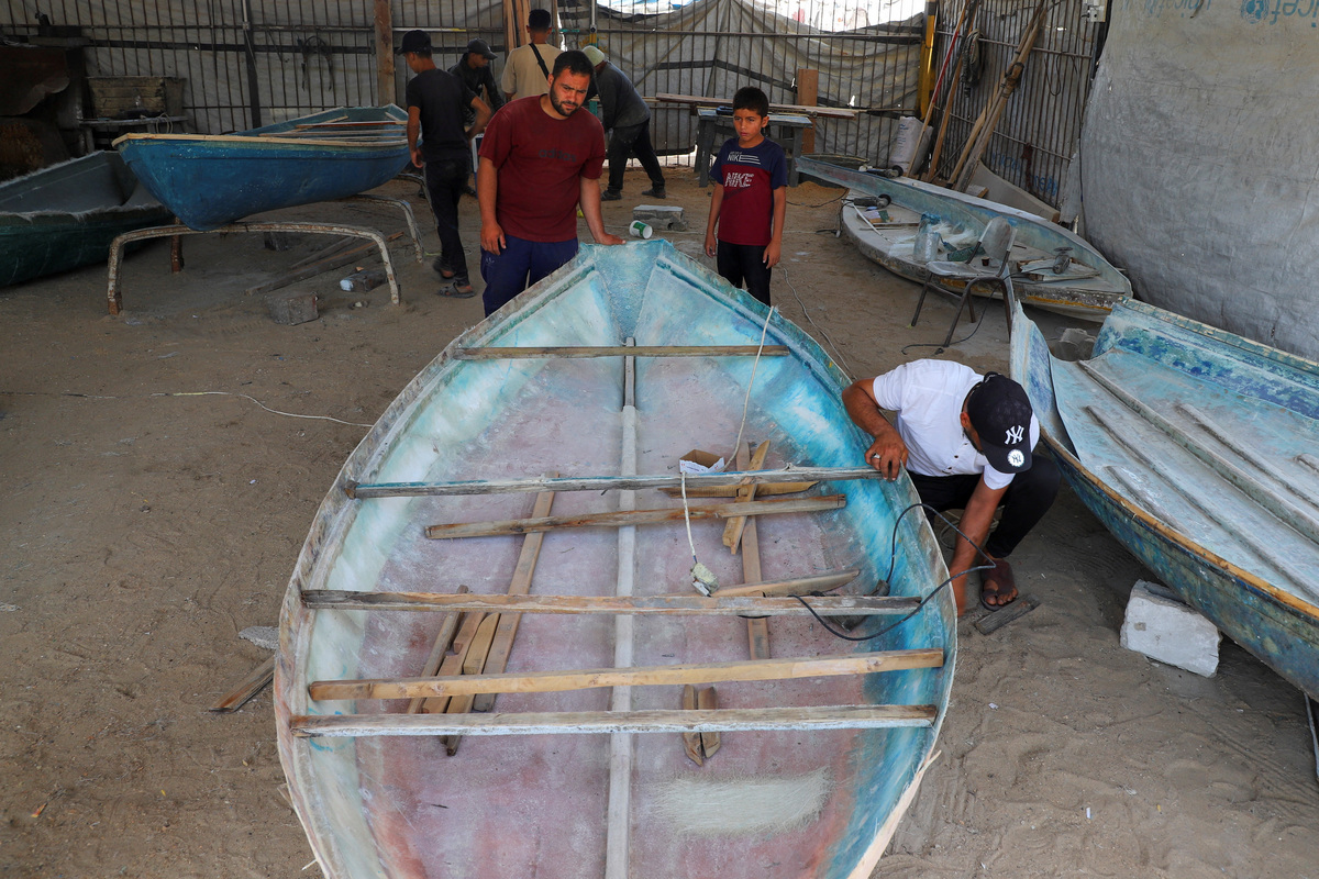 A Palestinian worker repairs a skiff damaged in the Israeli offensive, in Gaza City, June 3, 2026. REUTERS/Ebrahim Hajjaj