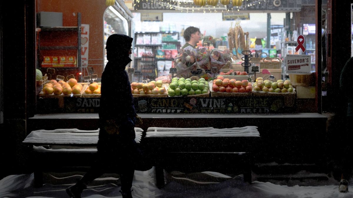 A pedestrian walks past a grocery store displaying fresh fruit during a winter snowstorm in Boston, Massachusetts, U.S., January 25, 2026.   REUTERS/Brian Snyder