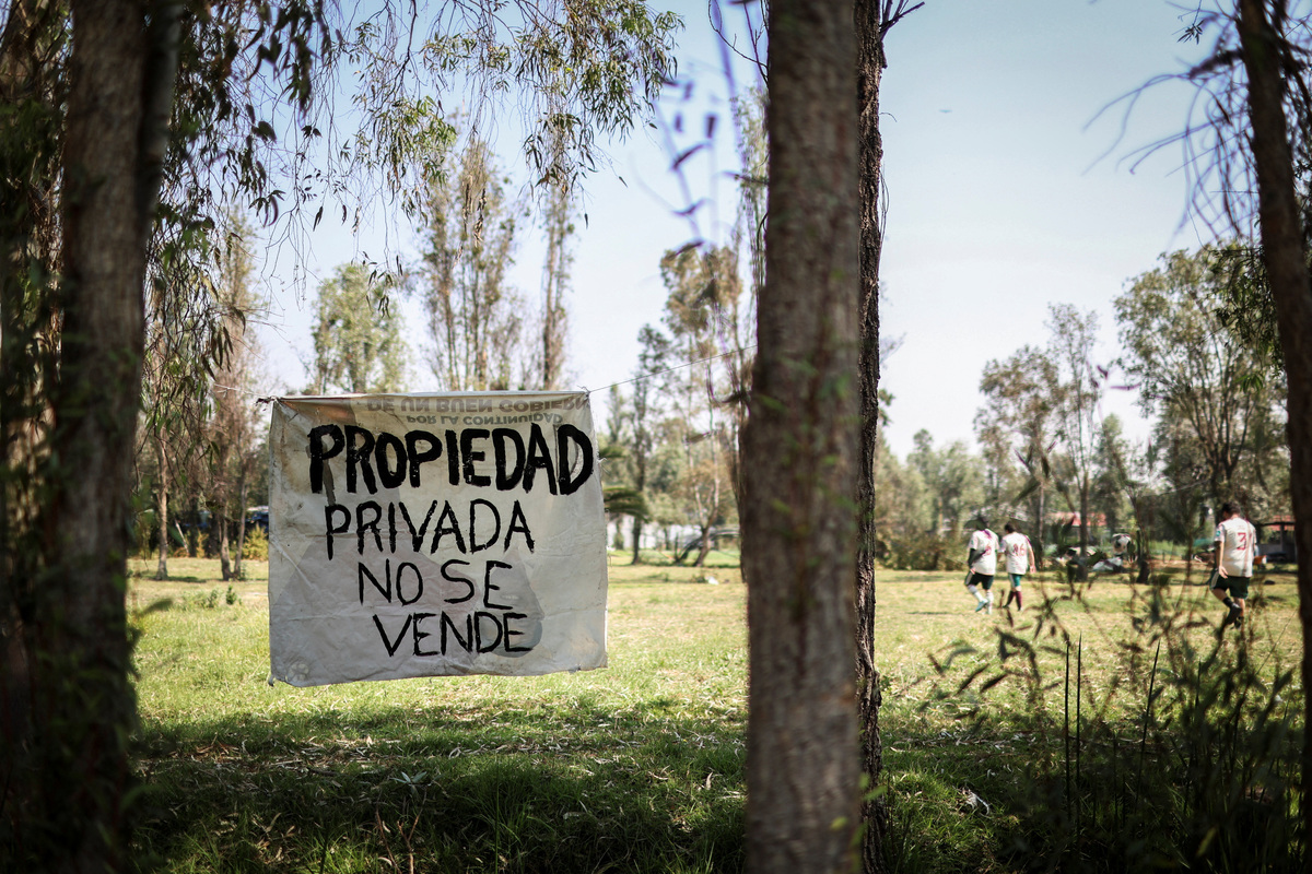 A sign reading "propiedad privada no se vende" (Private property is not for sale) hangs from trees on a chinampa bordering soccer fields in the protected Xochimilco area, in southern Mexico City, Mexico, March 8, 2026. The UNESCO World Heritage site is known for its canals and chinampas, or so‑called floating gardens, and strong community traditions, but a growing number of soccer fields is creating tension with farmers who advocate using chinampas solely for planting. REUTERS/Raquel Cunha
