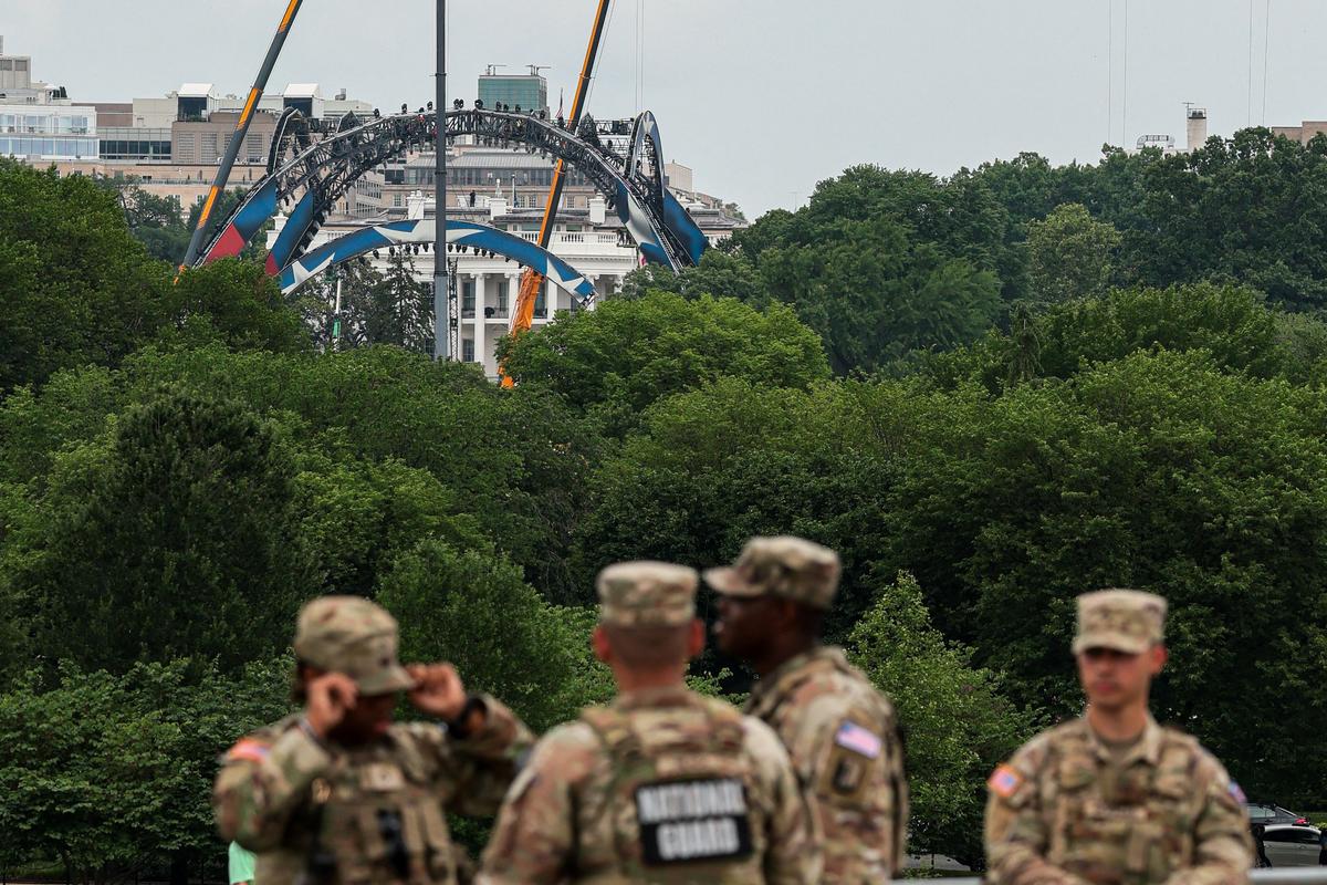 Members of the National Guard stand at the base of the Washington Monument, as construction on a temporary arena that will host the UFC Freedom 250 fight card in June on the South Lawn of the White House appears in the distance, in Washington, D.C., U.S., May 27, 2026. REUTERS/Kylie Cooper