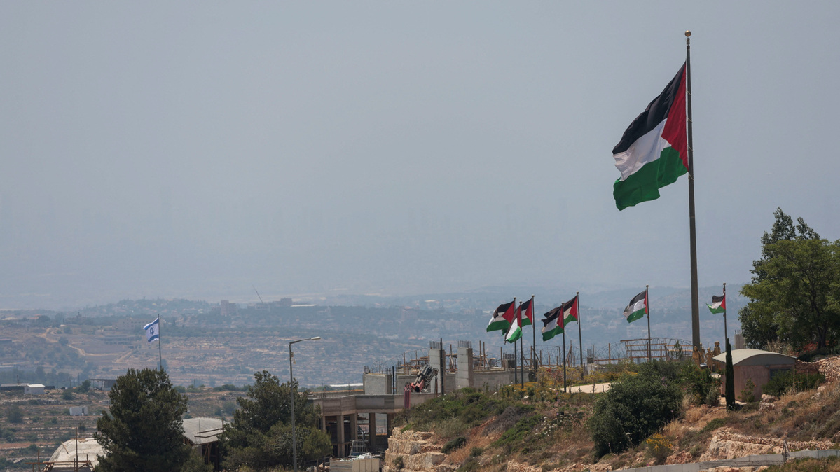An Israeli flag flutters at a new Israeli settlement, behind Palestinians flags near Ramallah, in the Israeli-occupied West Bank, Jun 1, 2026. REUTERS/Mohammed Torokman