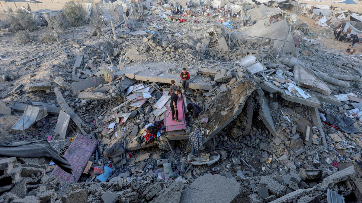 Palestinians inspect the site of an Israeli strike on a house whose residents were warned to evacuate before the attack, near a tent camp sheltering displaced people that was damaged in the strike, in Khan Younis in the southern Gaza Strip June 7, 2026. REUTERS/Ramadan Abed