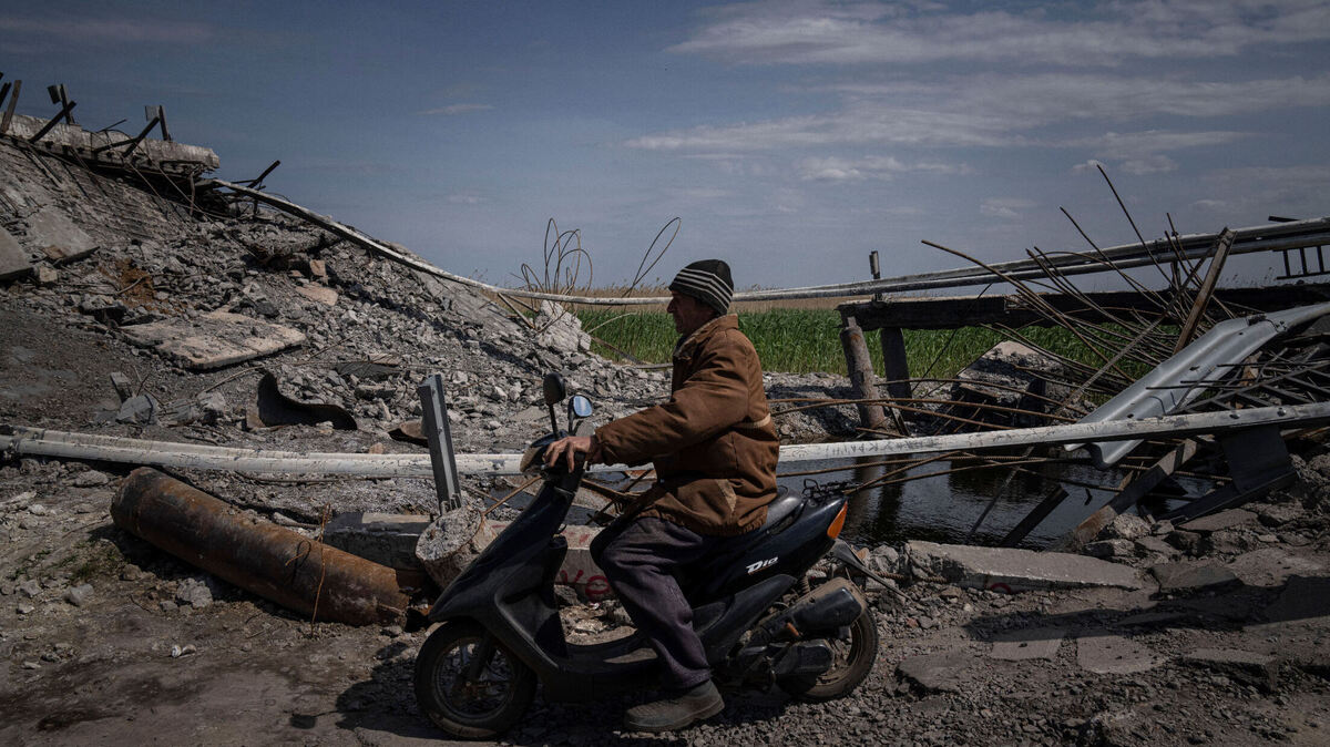 A man drives a scooter next to a bridge destroyed by shelling near Orihiv, Ukraine on May 5.