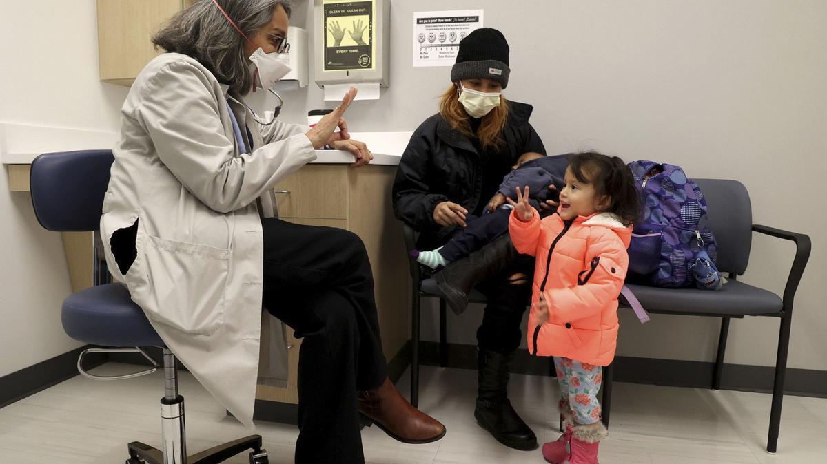 Dr. Pilar Guerrero, an emergency room doctor at Stroger Hospital, playfully counts with Yansa Torres, as her mother, Darling, holds her son, Yahir, at the Cook County Health Clinic in Chicago on Nov. 18, 2022. The clinic provides medical services to migrants arriving in Chicago. (Antonio Perez/Chicago Tribune/TNS)