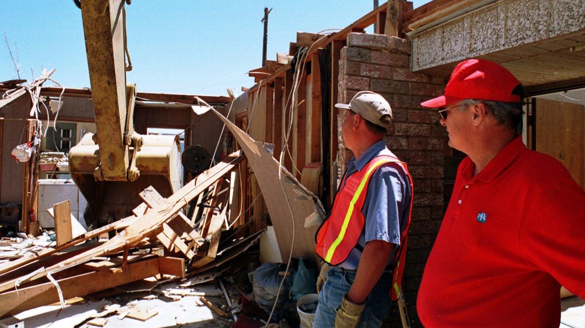 Mark Chase (R) and Jeff Morrison watch as a backhoe takes down the remains of Morrison's father's home in Moore, Okla., on May 7, 1999, four days after a tornado outbreak killed 50 people. File Photo by Ian Halperin/UPI