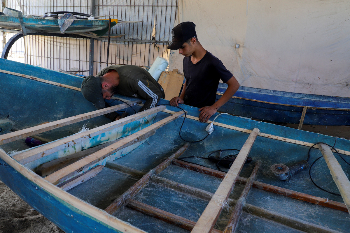 Palestinian workers repair a skiff damaged in the Israeli offensive, in Gaza City, June 3, 2026. REUTERS/Ebrahim Hajjaj