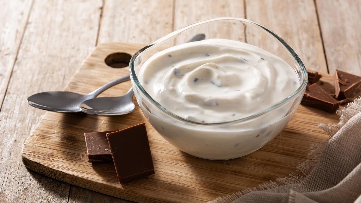 Stracciatella yogurt in transparent bowl isolated on wooden table