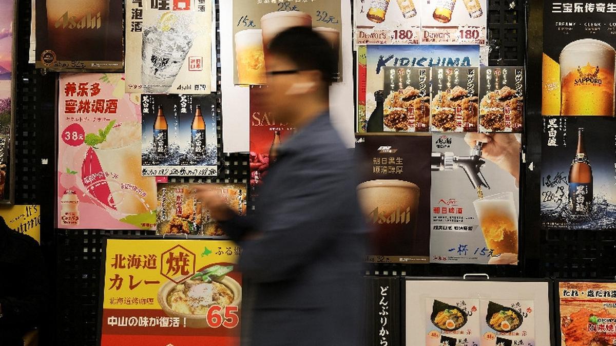 A person walks in front of food advertisement posters in the area of a shopping mall where several Japanese restaurants are located, in Shanghai, China, November 18, 2025.  REUTERS/Go Nakamura