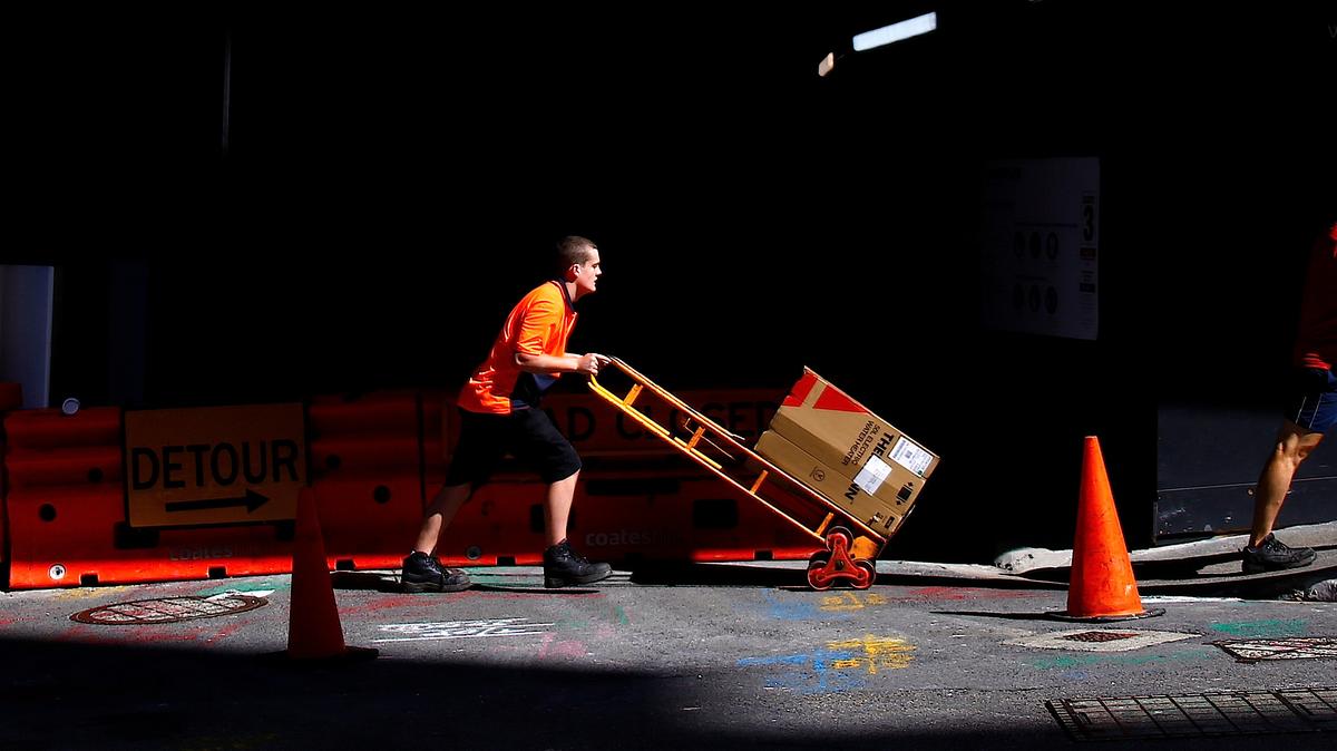 A worker pushes a trolley loaded with goods past a construction site in the central business district (CBD) of Sydney in Australia, March 15, 2018. REUTERS/David Gray