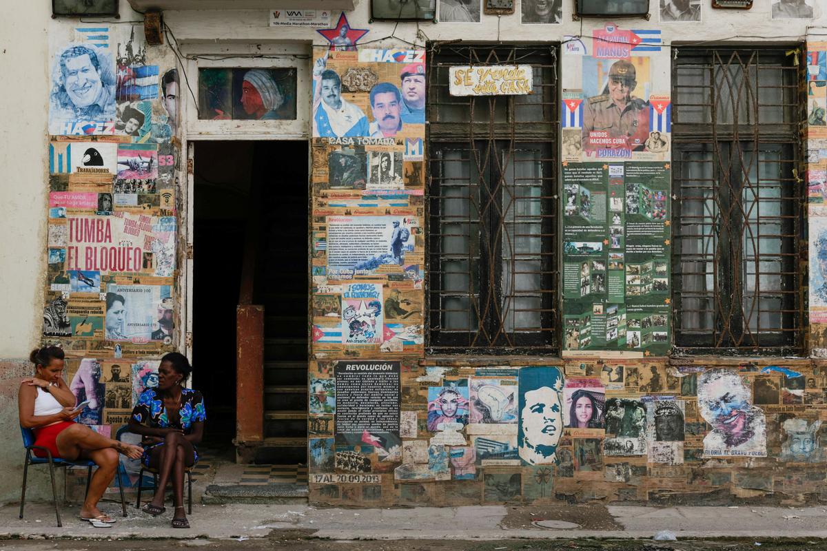 Women sit near a poster of former Cuban President Raul Castro, who has been indicted in the United States in a move that marks an escalation in Washington's pressure campaign against the Caribbean island's communist government, Havana, Cuba, May 20, 2026. REUTERS/Norlys Perez
