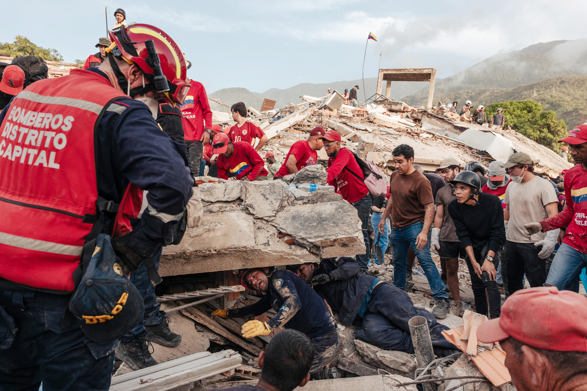 Rescue workers and civilians look for people trapped under the debris of buildings that collapsed during the country's double earthquake that struck the previous evening, in La Guaira, Venezuela, June 25, 2026. The Trump administration is signaling strong commitments of earthquake aid for Venezuela at a time when it has been expanding U.S. commercial interests beyond oil. (Adriana Loureiro Fernandez/The New York Times)