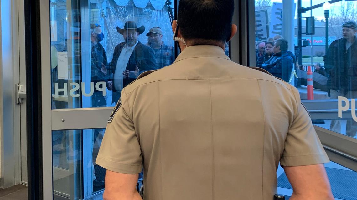 Anti-government activist Ammon Bundy, wearing a cowboy hat, yells through the closed Ada County Courthouse door at law enforcement officers inside Monday, March 15, 2021, in Boise, Idaho.