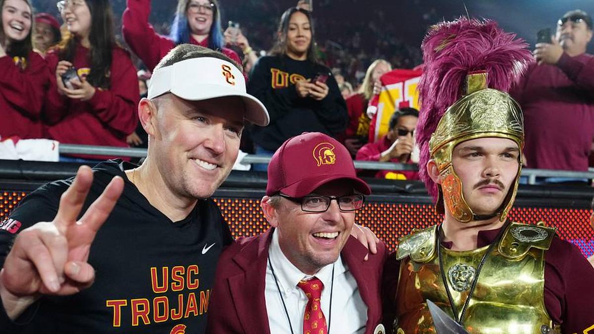  Nov 29, 2025; Los Angeles, California, USA; Southern California Trojans head coach Lincoln Riley (left) poses with Spirit of Troy marching band director James Vogel (center) and mascot Tommy Trojan after the game against the UCLA Bruins at United Airlines Field at Los Angeles Memorial Coliseum. Mandatory Credit: Kirby Lee-Imagn Images | Kirby Lee-Imagn Images 