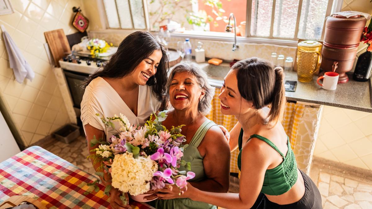 Young sisters giving flowers to grandmother at home