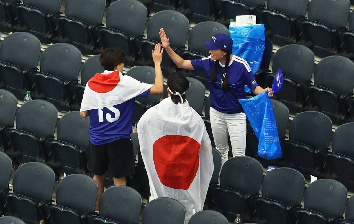  Japan fans clear rubbish from the stands after the match. 