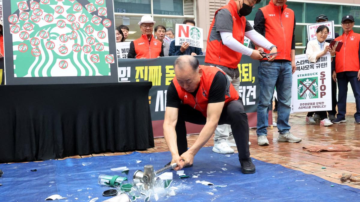 An activist smashes Starbucks tumblers and mugs during a protest against Starbucks' "Tank Day" campaign, which was launched on the same day as the anniversary of the May 18 Gwangju uprising, when the then military government sent in troops and tanks to suppress mass rallies for democracy, in Gwangju, South Korea, May 21, 2026. Yonhap via REUTERS