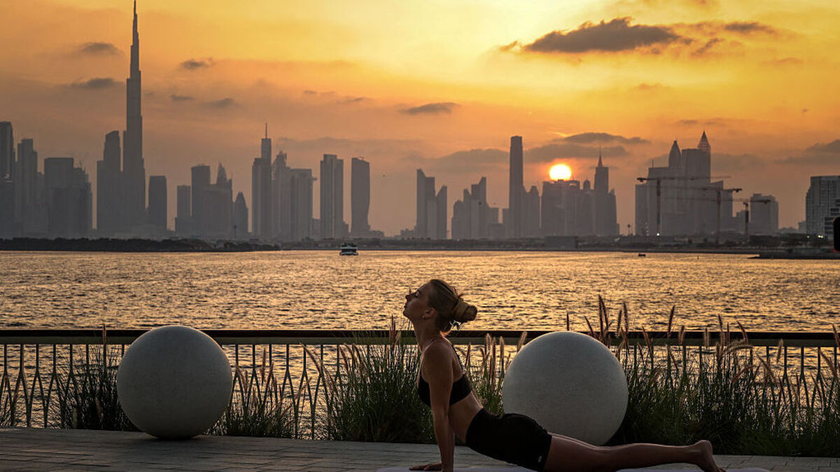 A woman practices yoga in front of the Dubai skyline, with the Burj Khalifa, the world's tallest building, seen from Creek Harbour on April 3, 2026. (Photo by FADEL SENNA / AFP via Getty Images)