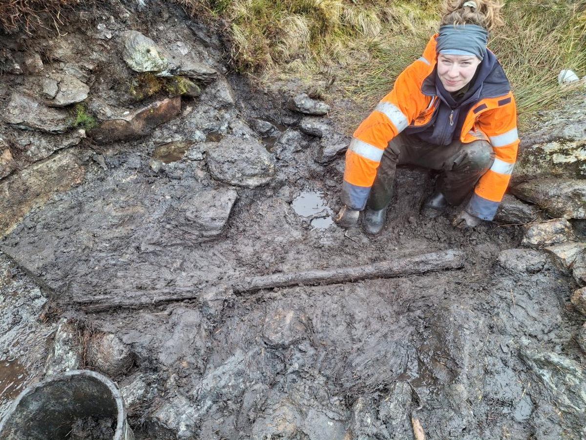  Archaeology Trainee Alice Connelly with the timber post at illicit whisky still site. (National Trust for Scotland via SWNS) 