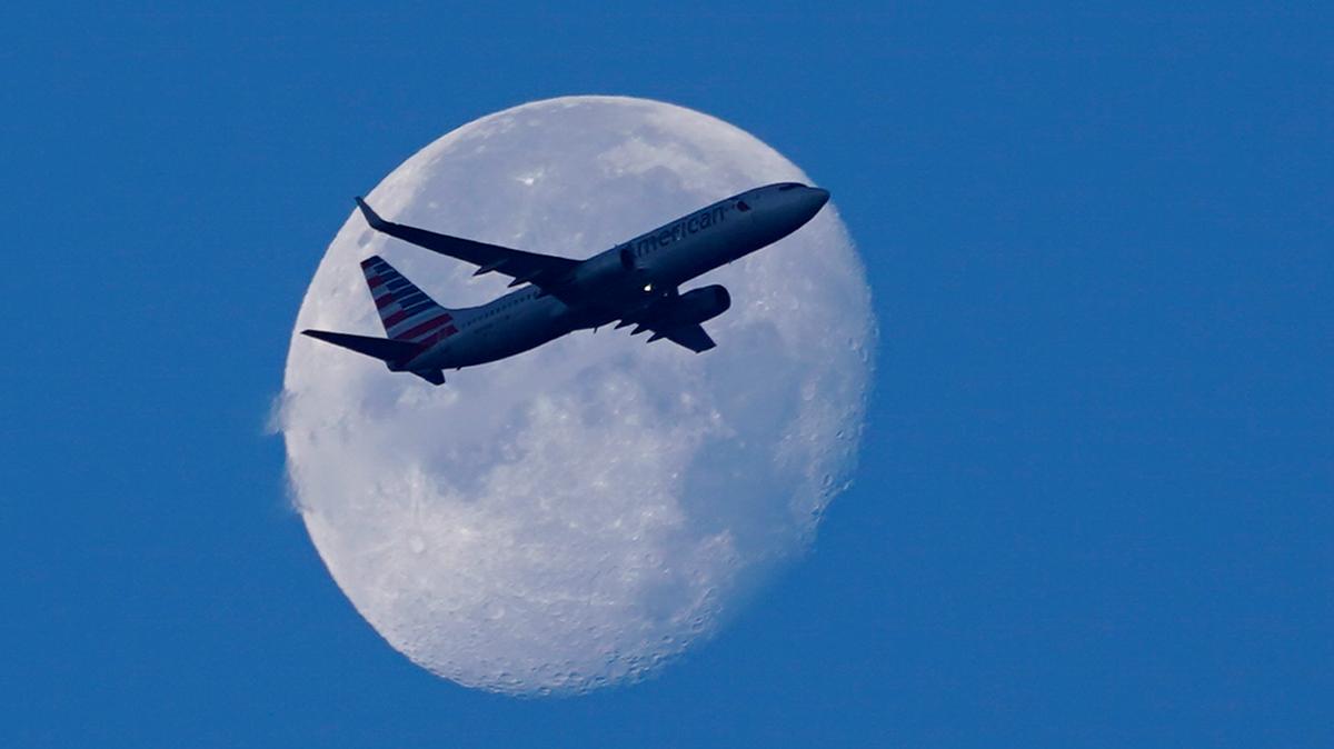 An American Airlines plane flies past the moon as it heads to Orlando from Miami International Airport on April 19.