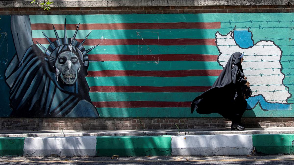 FILE PHOTO: A woman walks past the mural showing U.S. flag with barbed wire and the Statue Of Liberty with skull face in Tehran, Iran June 25, 2019.  Nazanin Tabatabaee/Nazanin Tabatabaee/West Asia News Agency via REUTERS/File Photo