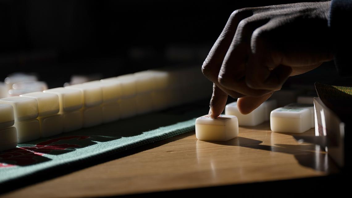 Demarcus Patterson goes to pick up a tile on his turn during a monthly meeting of the Honour Tile Society mahjong club on Saturday, Jan. 31, 2026, at Hot Shot Coffee in Denver. (Timothy Hurst/The Denver Post/TNS)