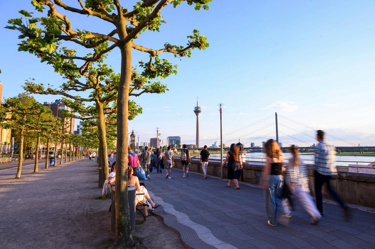 People walk at the promenade by the river Rhine with the skyline in the background including the Rheinturm in Duesseldorf, Germany, May 13, 2024. REUTERS/Jana Rodenbusch