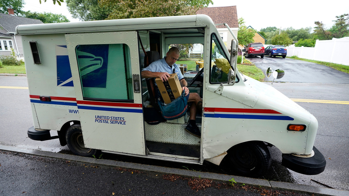 U.S. Postal Service carrier John Graham packs his mail bag after parking a 28-year-old delivery truck, Wednesday, July 14, 2021, in Portland, Maine. The Postal Service’s aging fleet of trucks is soldiering on even as a contract for greener replacement vehicles is being challenged. The primary fleet of vehicles that were delivered starting in 1987 is due to be replaced under a new contract, but the winning bid is being challenged. (AP Photo/Robert F. Bukaty)
