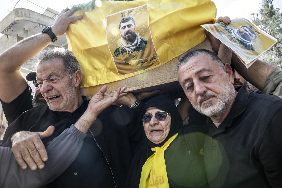 Mourners carry a coffin draped in the Hezbollah flag during a mass funeral for 20 people in the southern Lebanese village of Qlaileh, on Tuesday, April 21, 2026. The cease fire has given families who had fled because of Israeli evacuation warnings the opportunity to return to the village and bury their relatives killed during the war after being temporarily buried in transit cemeteries. (David Guttenfelder/The New York Times)