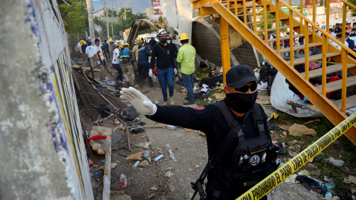 A police officer raises his arm to block photographers to to avoid taking pictures at the site of a trailer accident that left at least 49 people dead, most of them migrants from Central America, in Tuxtla Gutierrez, in Chiapas state, Mexico December 9, 2021. REUTERS/Jacob Garcia