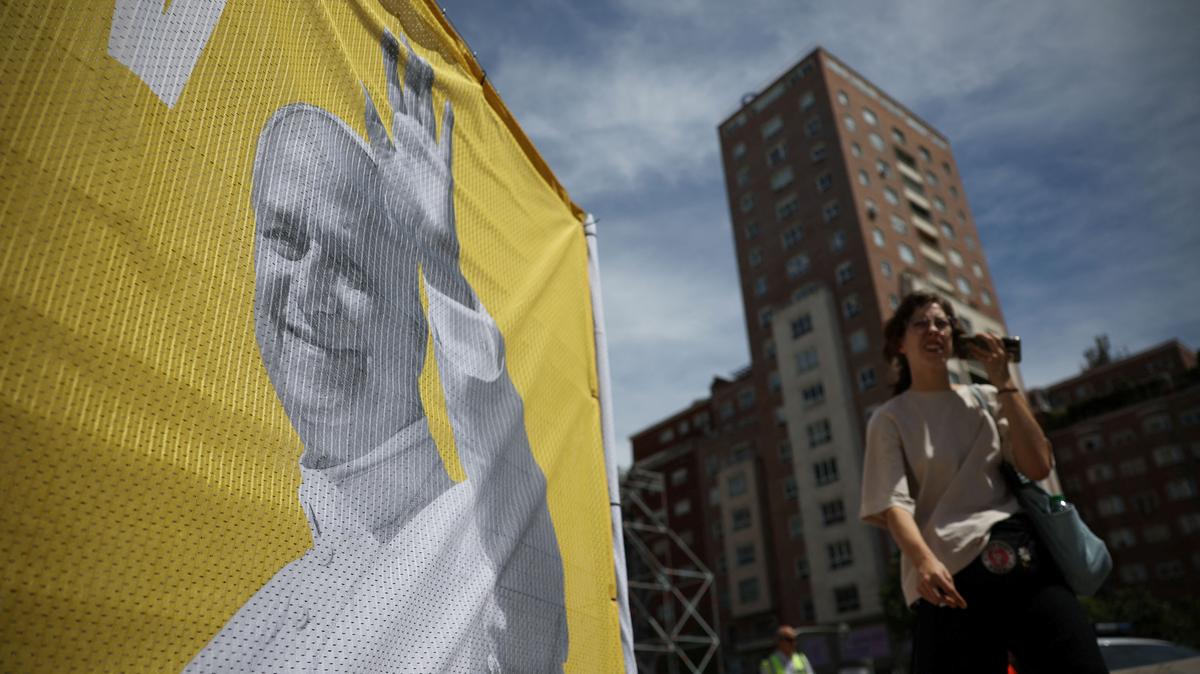 A person walks past a banner announcing the visit of Pope Leo XIV outside the Santiago Bernabeu Stadium in Madrid, Spain, June 2, 2026. REUTERS/Kacper Pempel