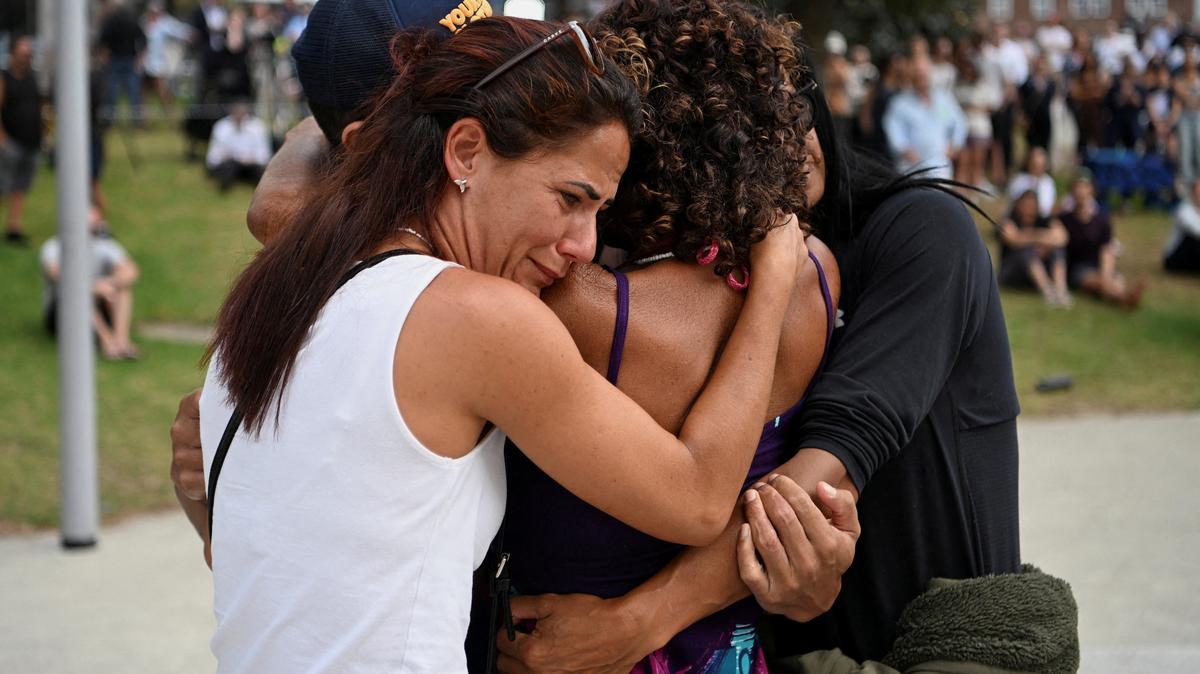 People embrace as they visit a makeshift memorial following the attack on a Jewish holiday celebration at Sydney's Bondi Beach, in Sydney, Australia, December 15, 2025. REUTERS/Flavio Brancaleone