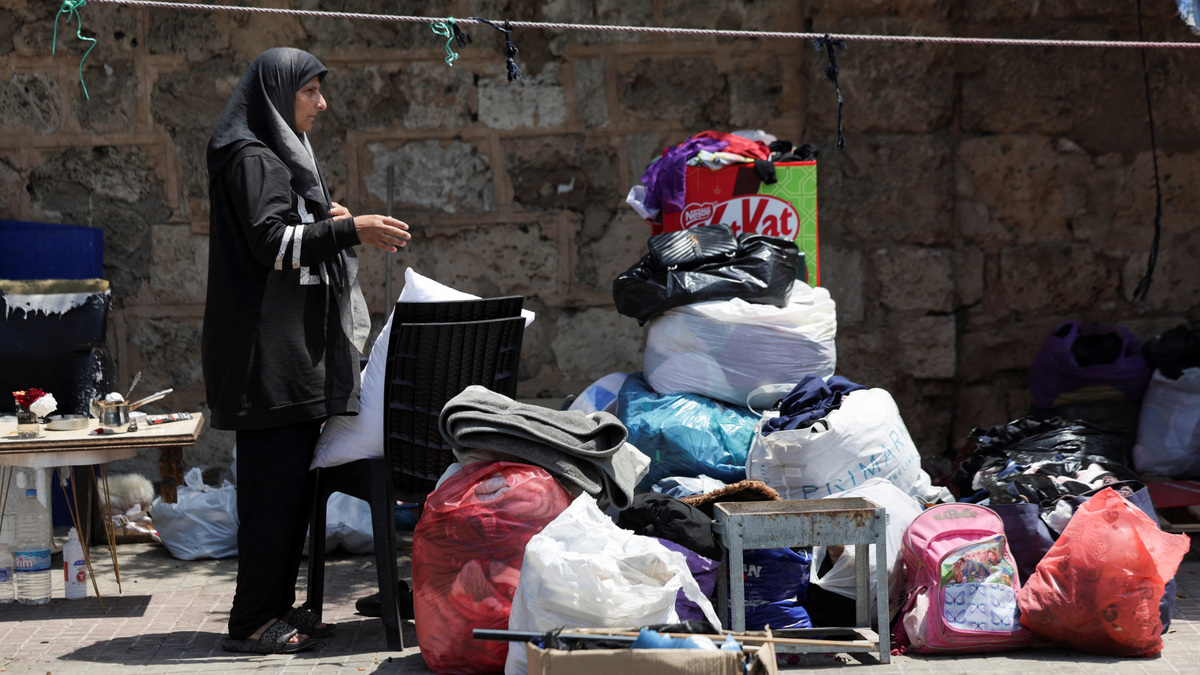 A woman stands near her belongings on a sidewalk in Beirut, where she and her family have been living in a tent, as she prepares to return home following an interim deal between the U.S. and Iran, in Beirut, Lebanon, June 24, 2026. REUTERS/Khalil Ashawi