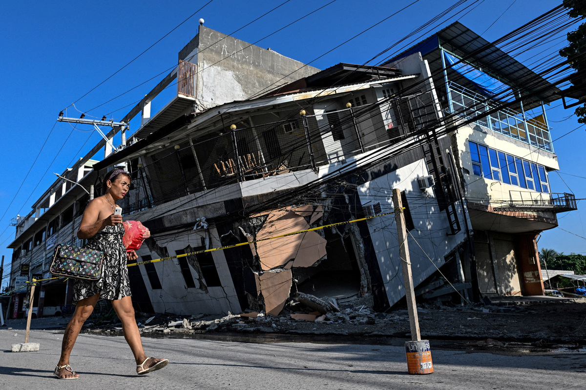 A woman walks past a collapsed building a day after the magnitude 7.8 earthquake, in Calumpang, General Santos, southern Philippines, June 9, 2026. REUTERS/Noel Celis
