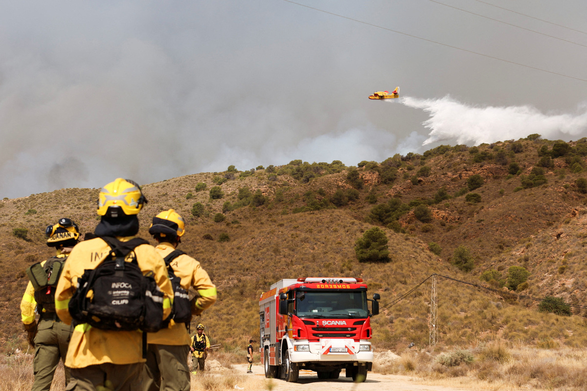 Forest firefighters look on as a firefighting plane dumps water during a wildfire in Los Gallardos, Almeria, Spain, July 10, 2026. REUTERS/Chema Artero