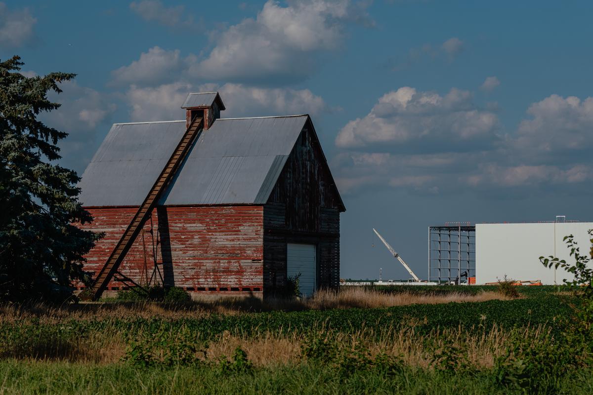 A cold storage warehouse rises in the distance beyond an old bard in Joliet, Ill. on July 1, 2025. Nearby, a proposed warehouse complex by NorthPoint Development, that would fill in thousands of acres of farmland, has been locked up in litigation for almost a decade. (Jamie Kelter Davis/The New York Times)....