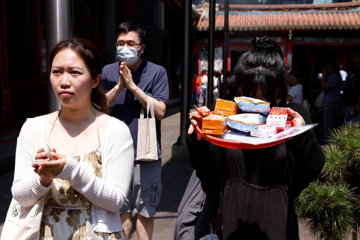 A BTS fan prays with snacks, group merchandise, concert seat maps and a wish list to Yue Lao, the god of love in Chinese mythology who oversees relationships and marriage, at Taipei’s Bangka Lungshan Temple, in hopes of securing a concert ticket, in Taipei, Taiwan, May 30, 2026. REUTERS/Ann Wang