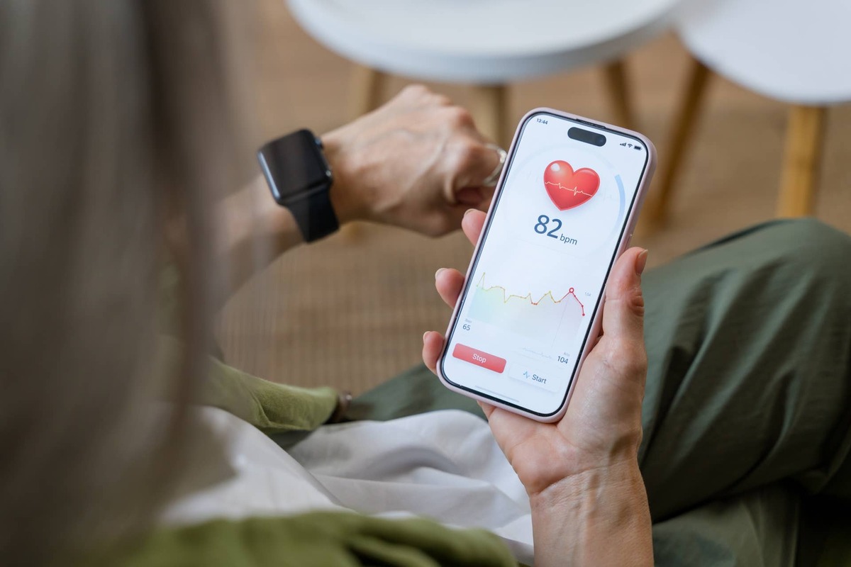  Person checking health data on a smartphone app linked to a smartwatch.