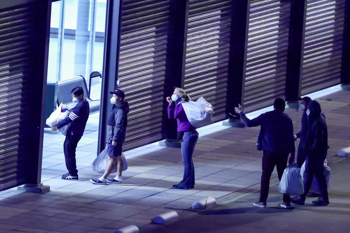 Passengers evacuated from the cruise ship MV Hondius, which was affected by a hantavirus outbreak, walk with their belongings after disembarking at Eindhoven Air Base, Netherlands, May 12, 2026. REUTERS/Piroschka van de Wouw