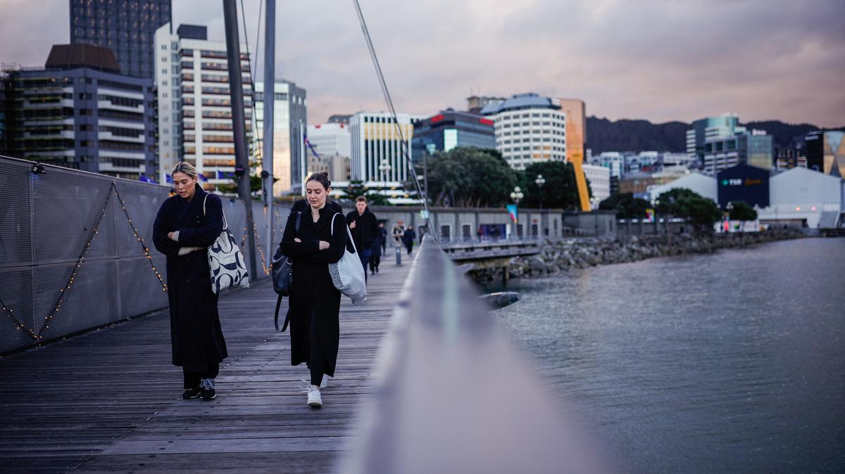 People walk alongside the sea in Wellington, New Zealand August 3, 2023. REUTERS/Amanda Perobelli