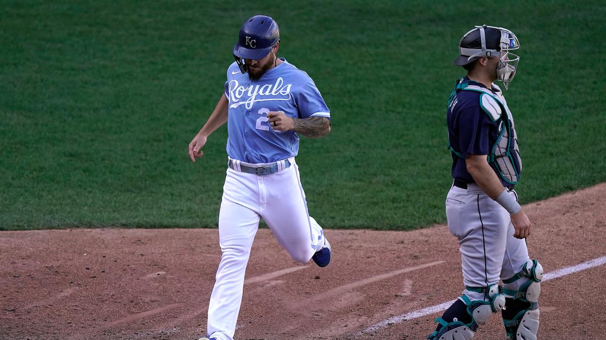 Kansas City Royals’ Kyle Isbel crosses the plate behind Seattle Mariners catcher Cal Raleigh to score on a single by Hunter Dozier during the sixth inning of a baseball game against the Seattle Mariners Sunday, Sept. 25, 2022, in Kansas City, Mo. The Royals won 13-12. (AP Photo/Charlie Riedel)