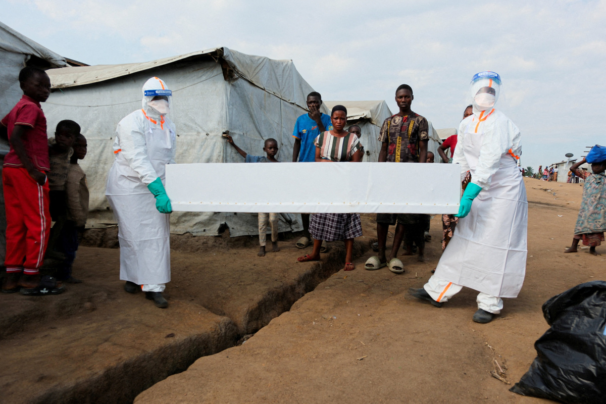 Health workers wearing personal protective equipment (PPE) carry the coffin of a person who is suspected to have died from Ebola for burial at the Kigonze displaced persons camp, one month after an Ebola outbreak was declared, in Bunia, eastern Democratic Republic of Congo, June 18, 2026. REUTERS/Gradel Muyisa Mumbere