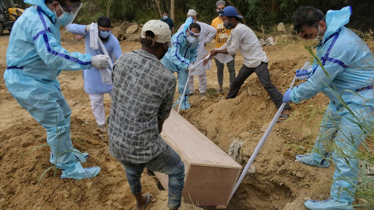 Familiares entierran a un pariente que falleció de COVID-19, el martes 4 de mayo de 2021 en un cementerio de Nueva Delhi, India.