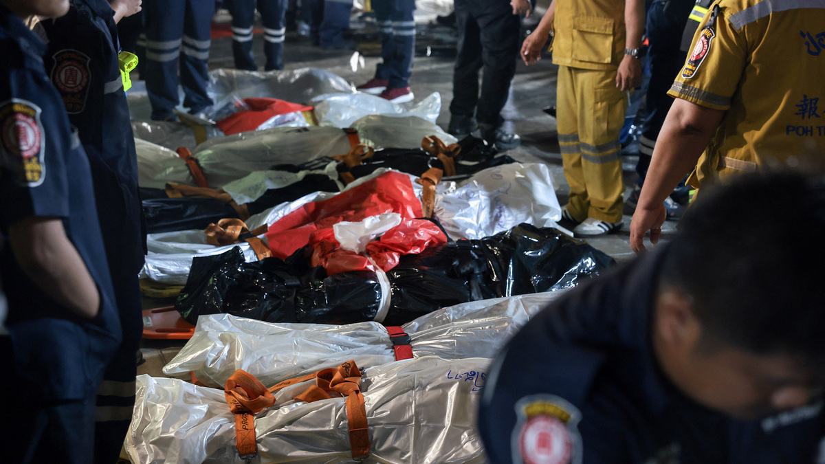 Members of emergency personnel work next to covered bodies at the site of a deadly fire at a pub in Bangkok, Thailand, July 13, 2026. REUTERS/Chalinee Thirasupa