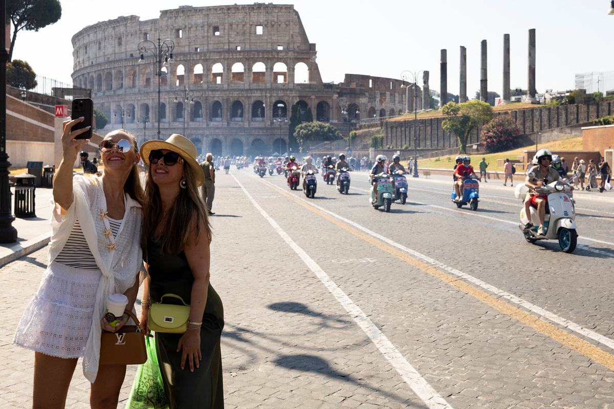 People take a selfie as Vespa riders drive past the Colosseum the last day of “Vespa Roma 2026 - 80 Years of an Icon”, a four-day global gathering marking the 80th anniversary of the iconic Italian scooter brand, in Rome, Italy, June 27, 2026. REUTERS/Remo Casilli