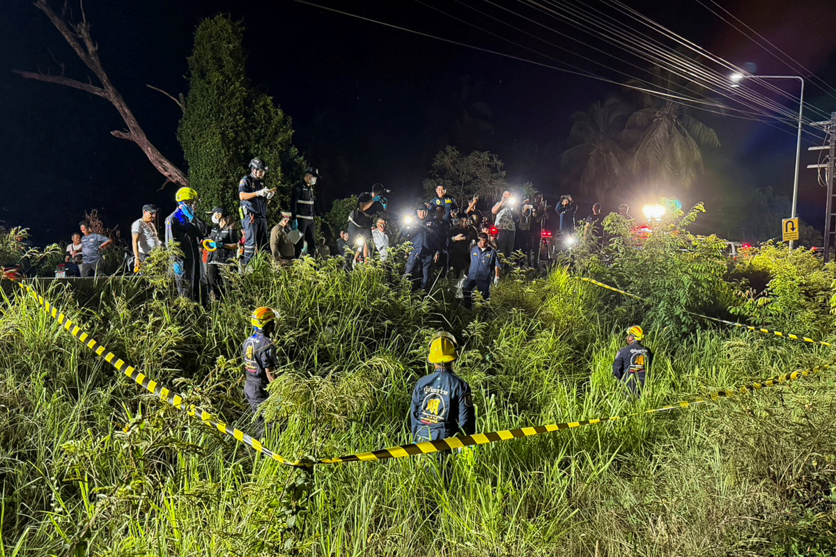 Rescue workers, police officers and forensic technicians search a grassy area near a railway track before police found a suitcase containing the body of a 17-year-old Thai girl in Pattaya City, Thailand, June 27, 2026. Picture taken with a mobile phone. REUTERS/Teerasak Suttativong