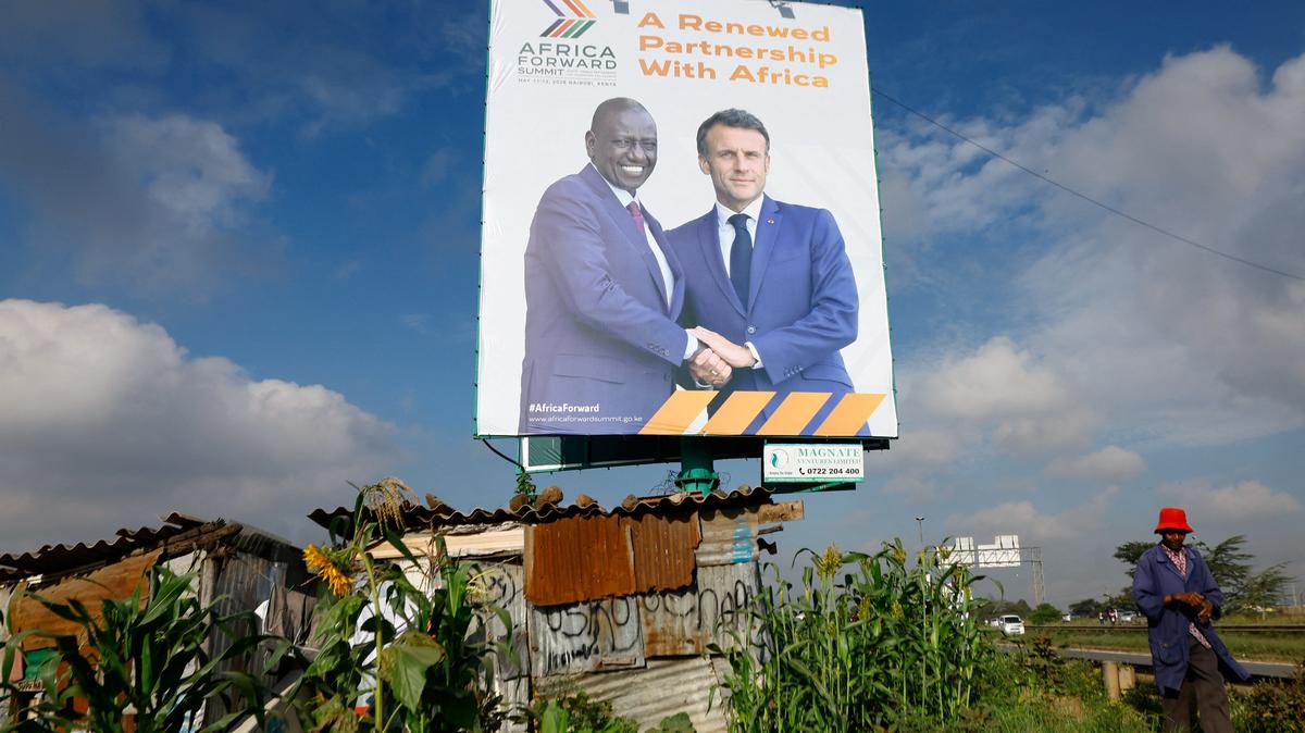 A pedestrian walks near a billboard featuring Kenyan President William Ruto and French President Emmanuel Macron ahead of the "Africa Forward" Summit, in the outskirts of Nairobi, Kenya May 7, 2026. REUTERS/Thomas Mukoya