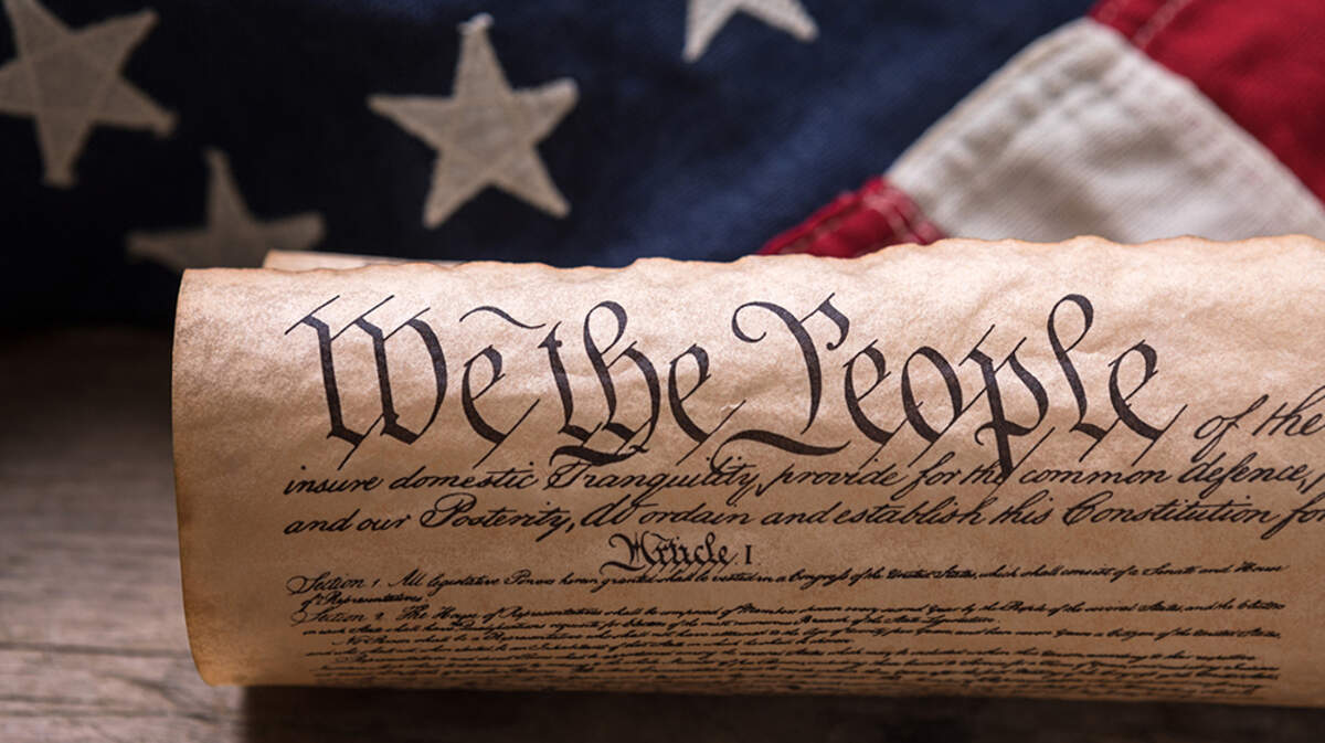 A photo illustration of the U.S. Constitution and an American flag.