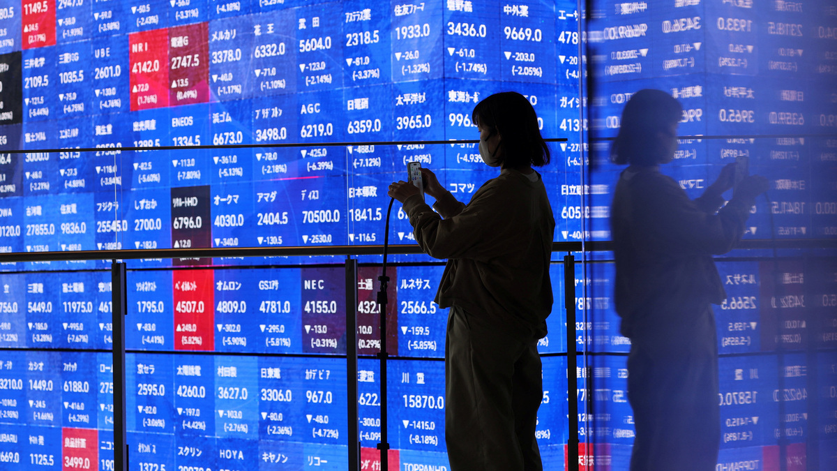 A visitor stands next to an electronic screen displaying Japan's Nikkei stock prices quotation board inside a conference hall in Tokyo, Japan March 4, 2026. REUTERS/Issei Kato