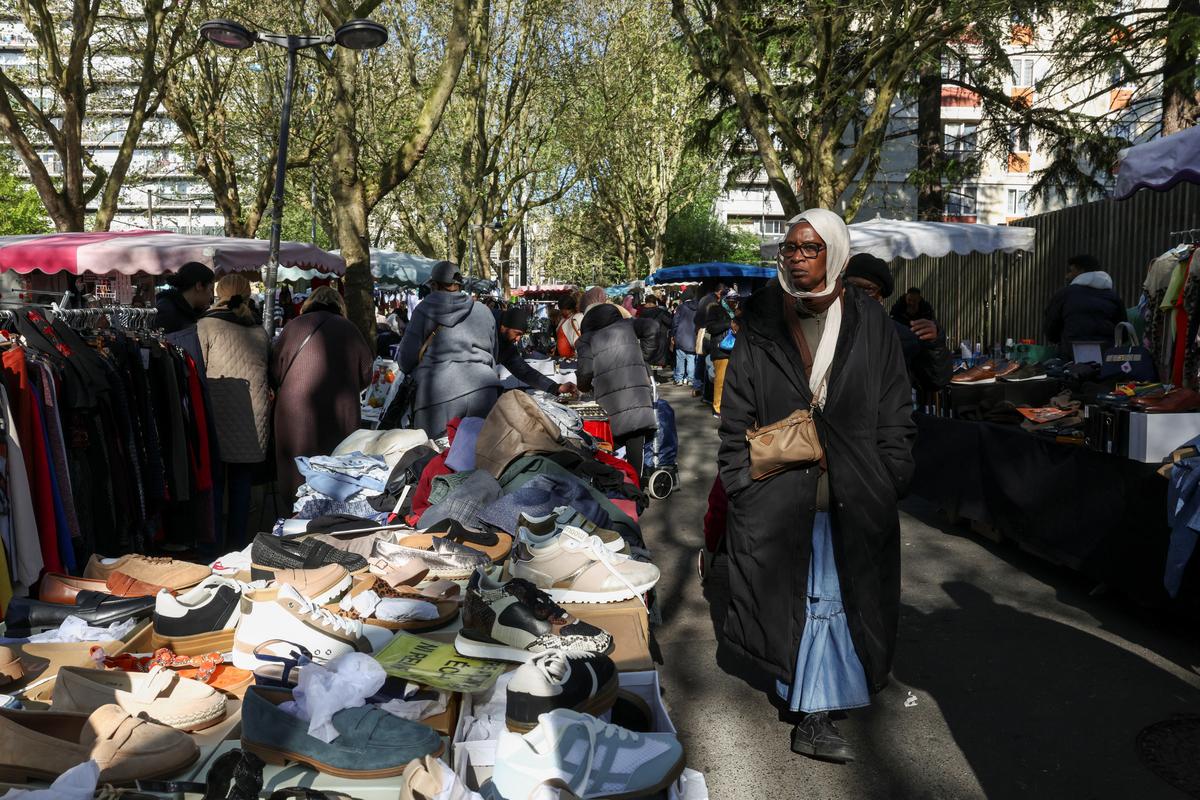A shopper walks through the 800 metre-long Tuesday Market in Sarcelles, which has vendors selling food, clothing, homeware products and handicrafts to cater for Sarcelles' diverse immigrant community in the Paris suburb of Sarcelles, France, April 14, 2026. REUTERS/Tom Nicholson