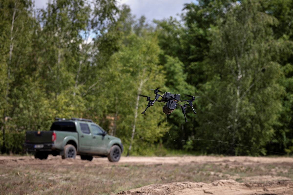 A drone that is controlled through a fiberoptic cable flies near a pickup that is equipped with Telearmy remote-driving capabilities at a defense technology event organized by the defence accelerator Defence Builder, amid Russia's attack on Ukraine, in an unspecified location in Ukraine, May 30, 2026. REUTERS/Thomas Peter